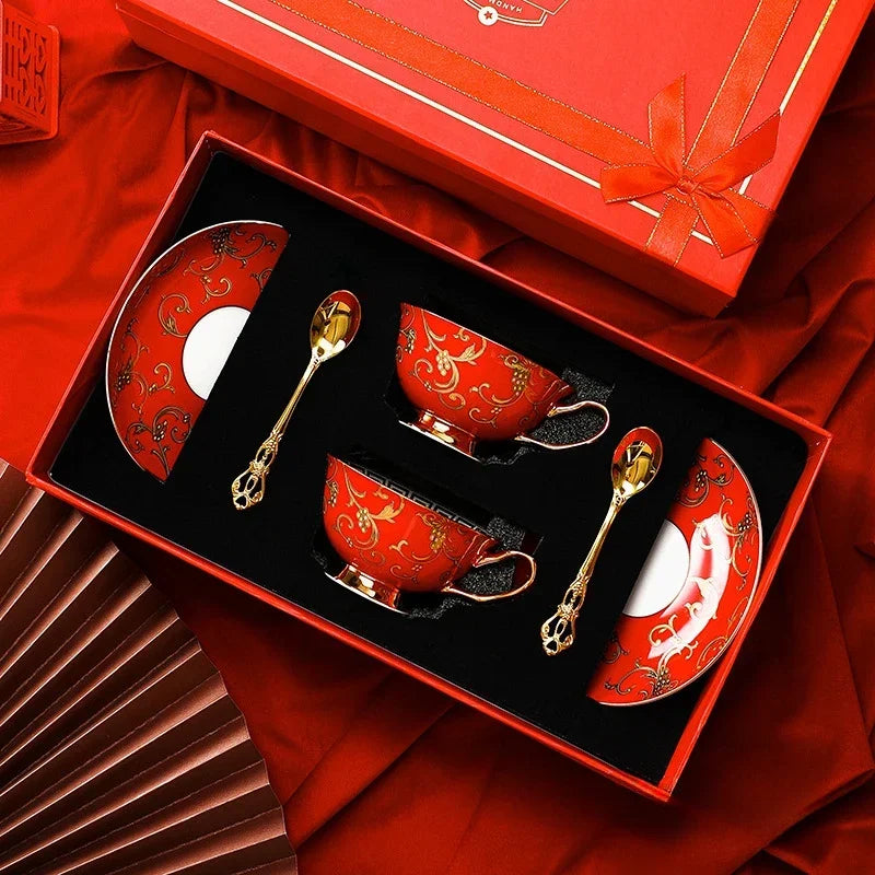 Red coffee set with gold accents in a matching box on a red fabric background