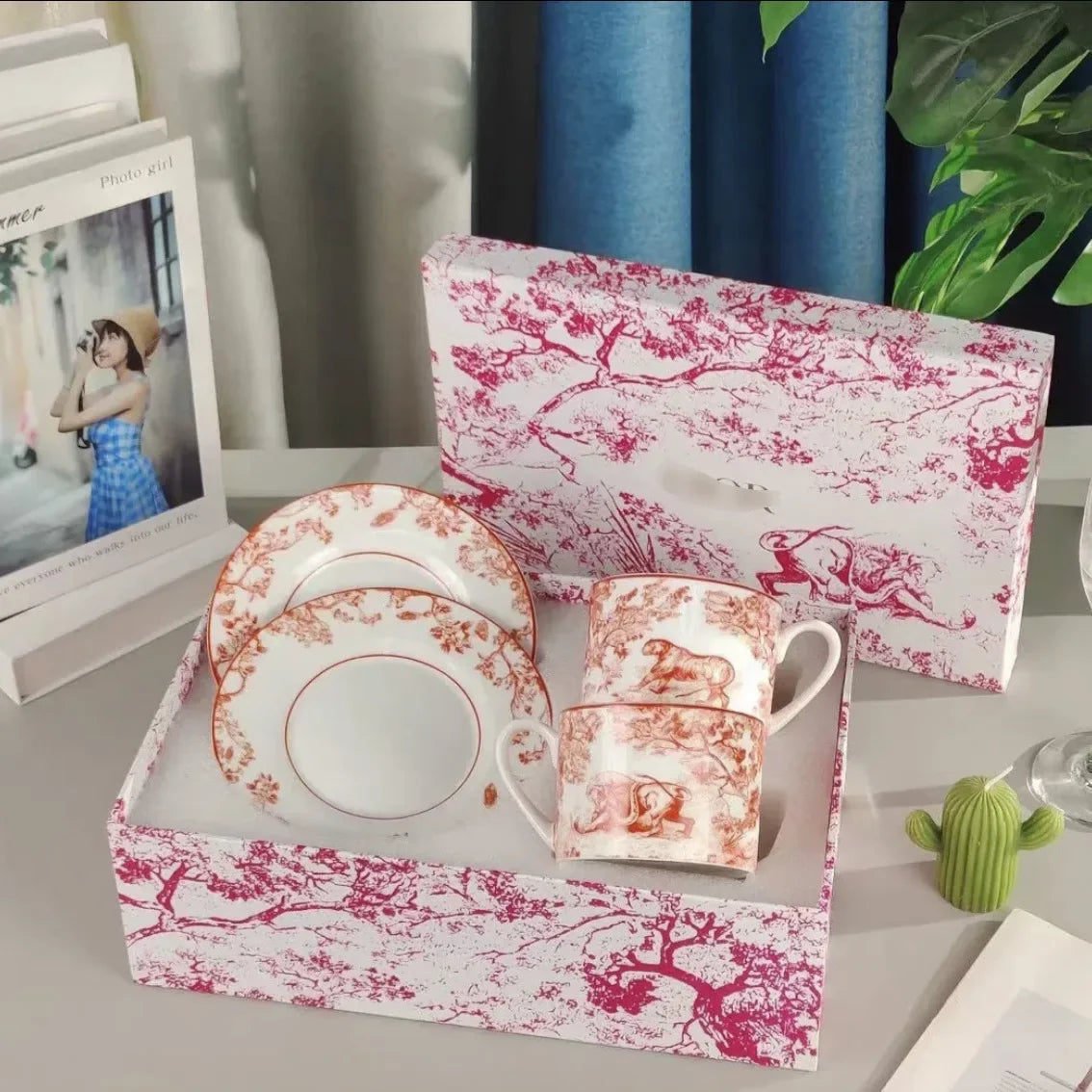 Ceramic coffee set with pink floral design on a matching box, placed on a surface.