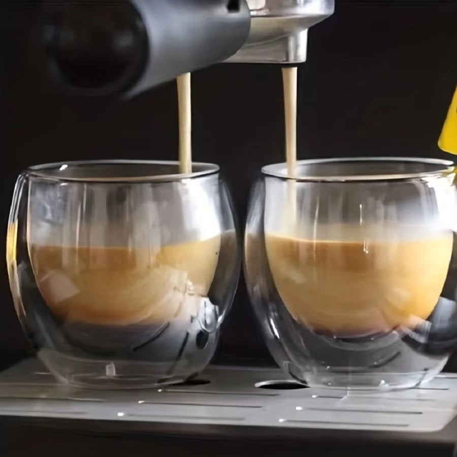 Espresso being poured into two glass cups from a coffee machine.