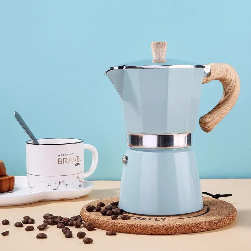Light blue espresso maker with wooden handle on a cork trivet against a light blue background.