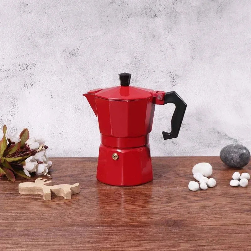 Red stovetop espresso maker on a wooden surface with decorative items.