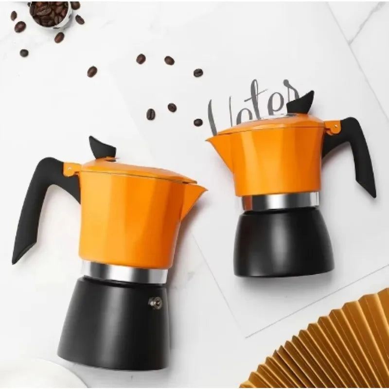 Two orange and black coffee percolators on a white surface with scattered coffee beans.